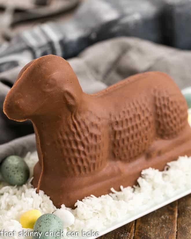 Fudge Lamb side view on a white tray of coconut on blue Easter eggs