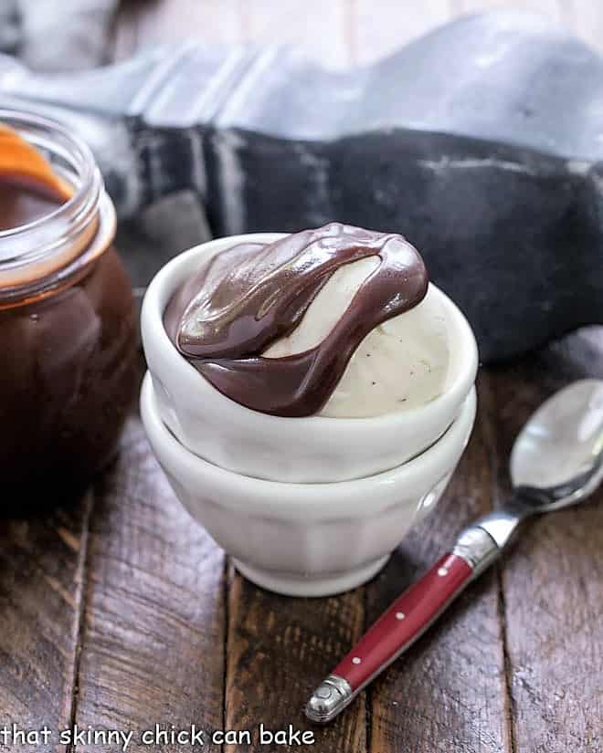 Hot Fudge Sauce over a scoop of vanilla ice cream in stackeed white bowls.