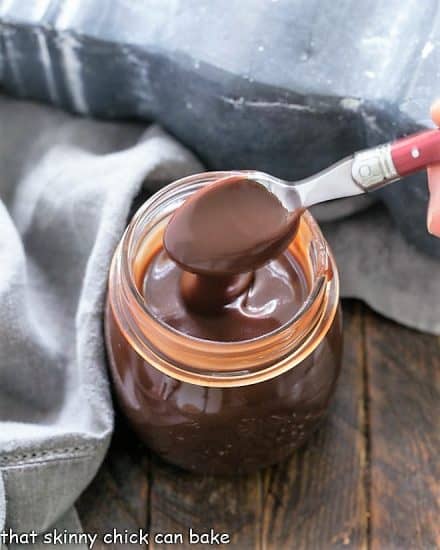 Jar of homemade hot fudge sauce with a spoonful being removed.