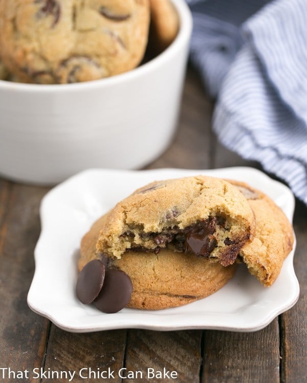 The New York Times Chocolate Chip Cookies with one broken open on a white square plate.