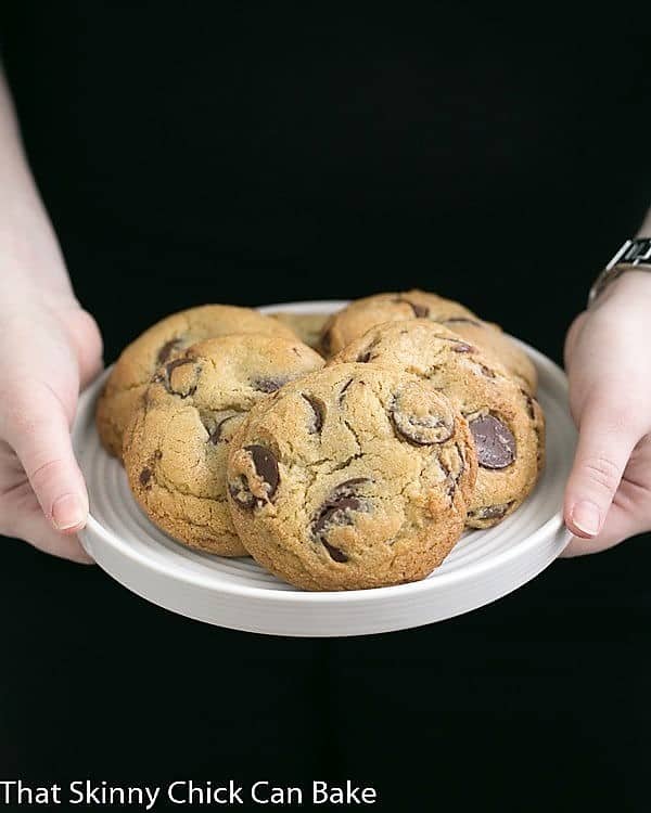 Jacques Torres' Secret Chocolate Chip Cookies on a white plate held by a girl's hands