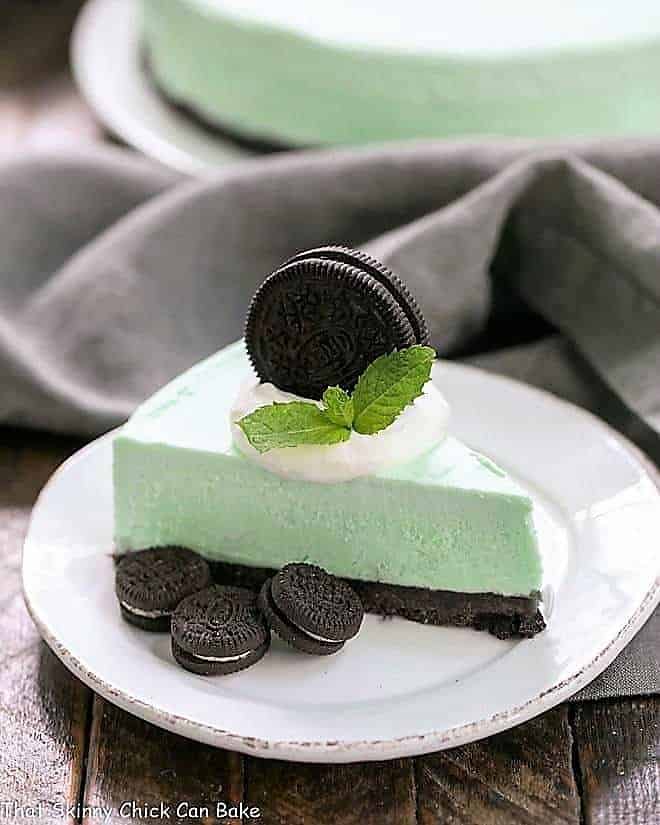 Frozen Grasshopper Pie with an Oreo Crust on a small round white plate topped with cream and an Oreo.