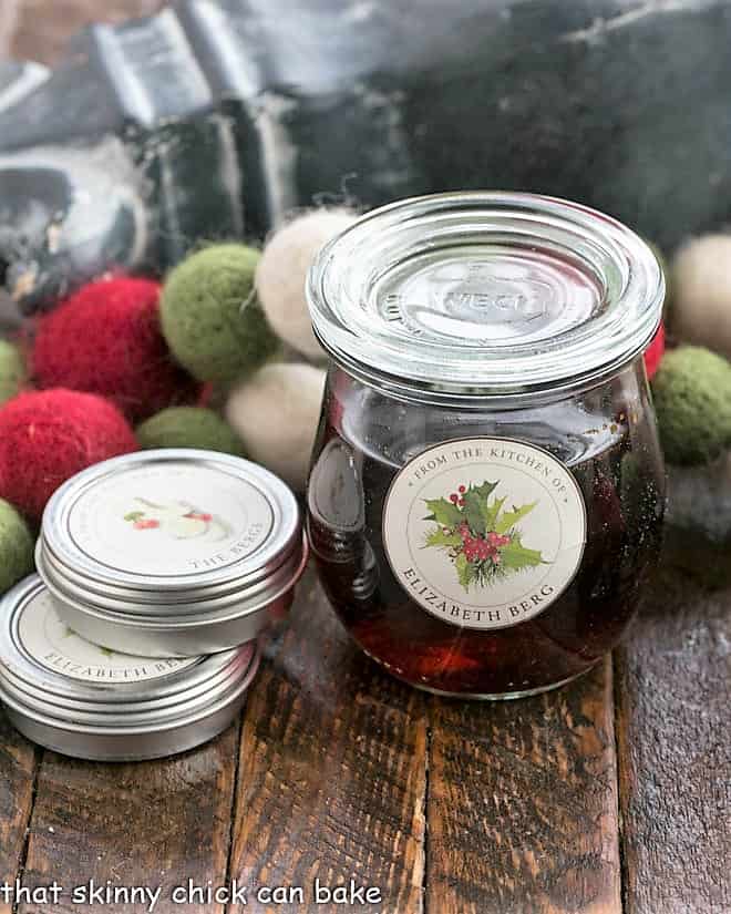 A Weck jar filled with homemade vanilla next to 2 tins of labels.