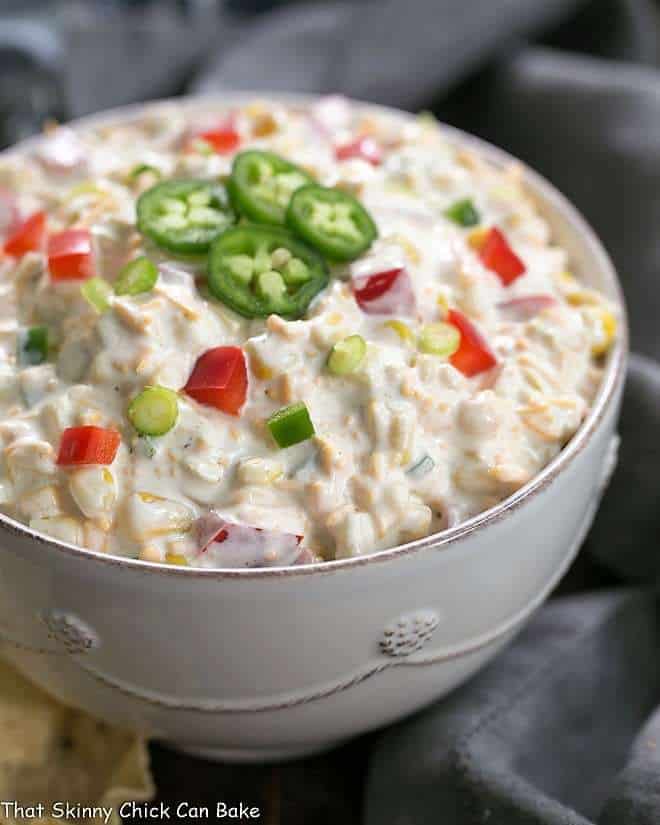 Sour Cream Corn Dip side view in a white ceramic bowl garnished with jalapeno slices.