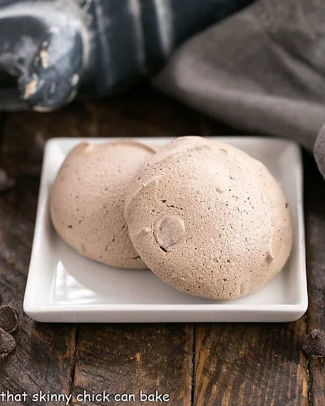Two Chocolate Chip Meringues on a square white plate