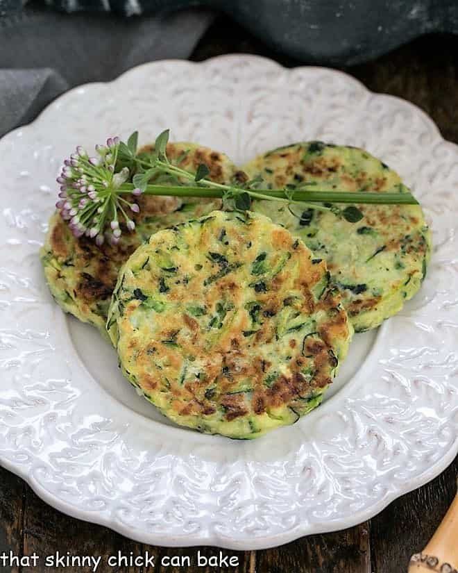 Overhead view of 3 zucchini fritter on a fancy, decorative white plate