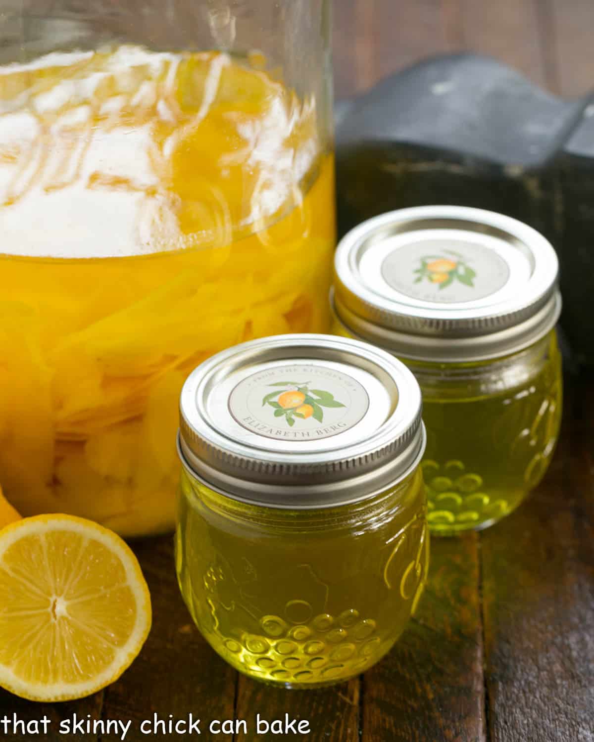 Limoncello recipe in a large canning jar plus two smaller gars and half a fresh lemon.