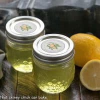 2 jars of homemade limoncello next to a whole and half lemon