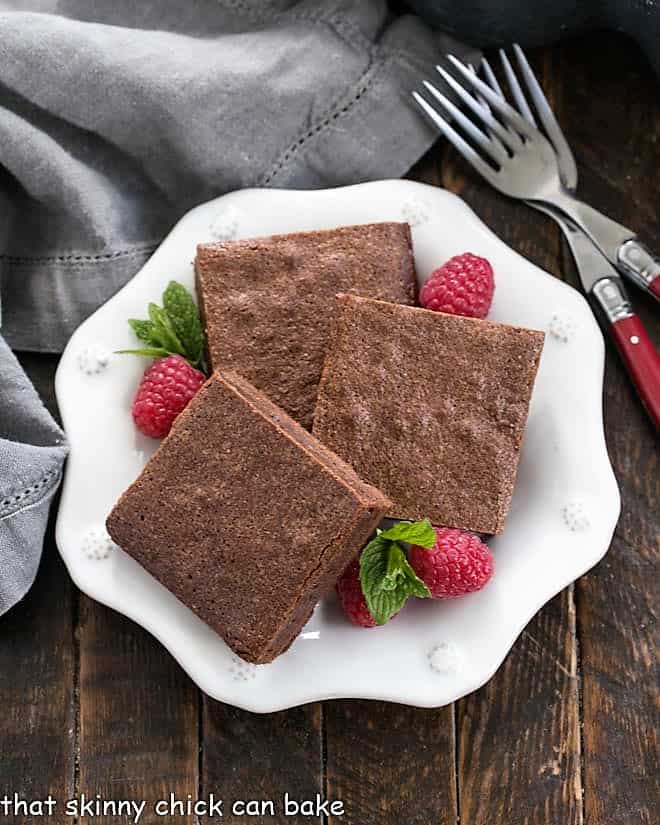 3 of Gale Gand's fudgy brownies on a decorative serving plate with raspberries and mint