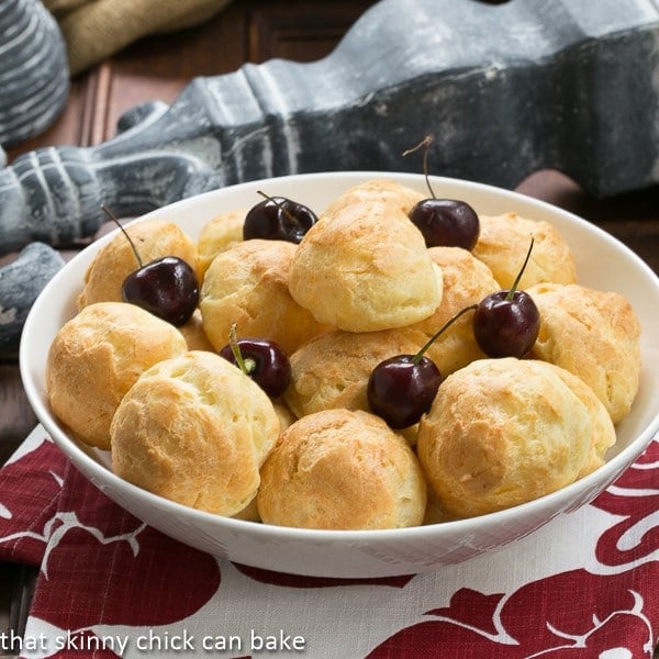 Gougères AKA French Cheese Puffs - a savory cream puff that is a marvelous appetizer Gougères in a white ceramic bowl on a red and white napkin
