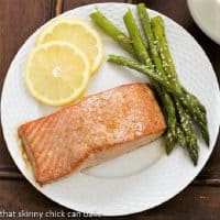 Overhead view of Grilled Cedar Plank Salmon on a white plate with asparagus and lemon slices