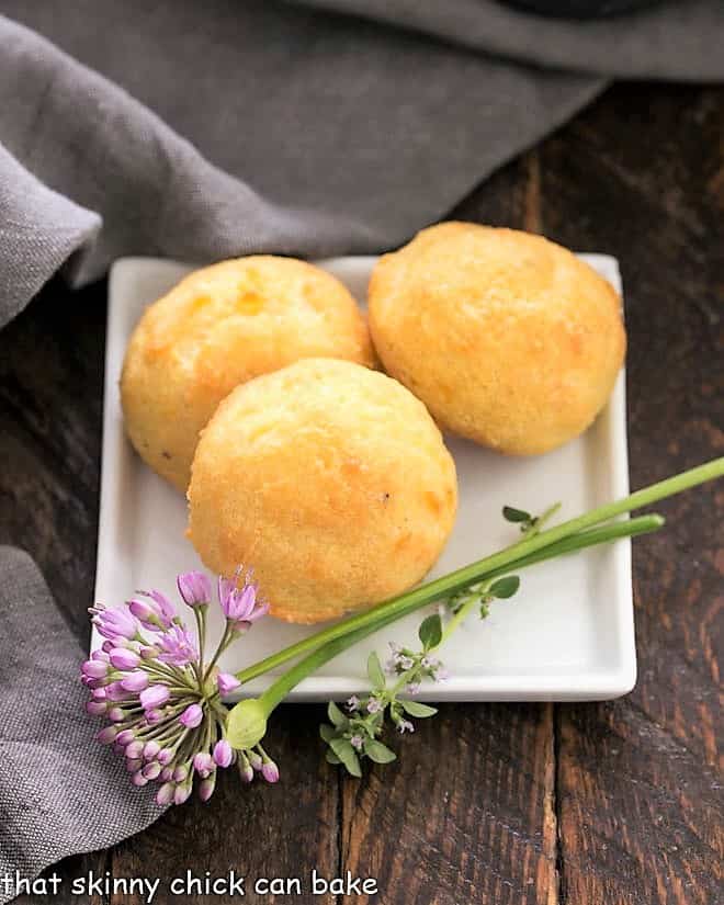 3 cheese puffs on a square white plate.