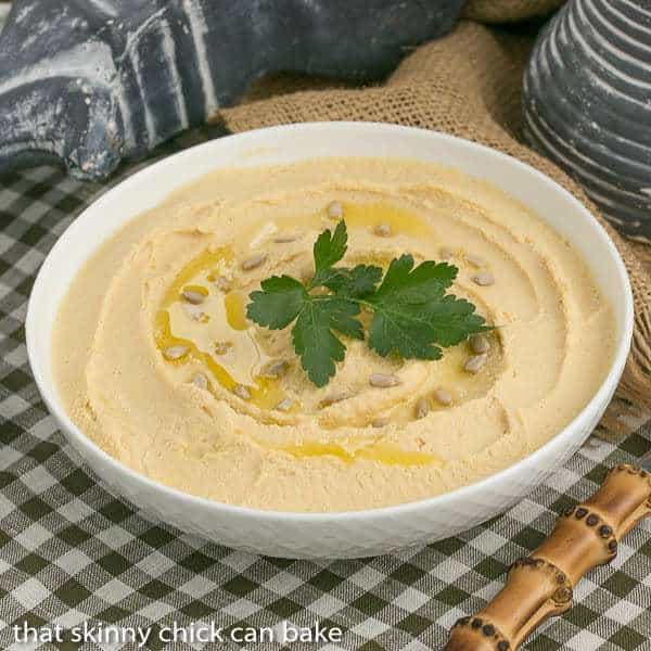 Lebanese Hummus in a white bowl garnished with seeds and parsley