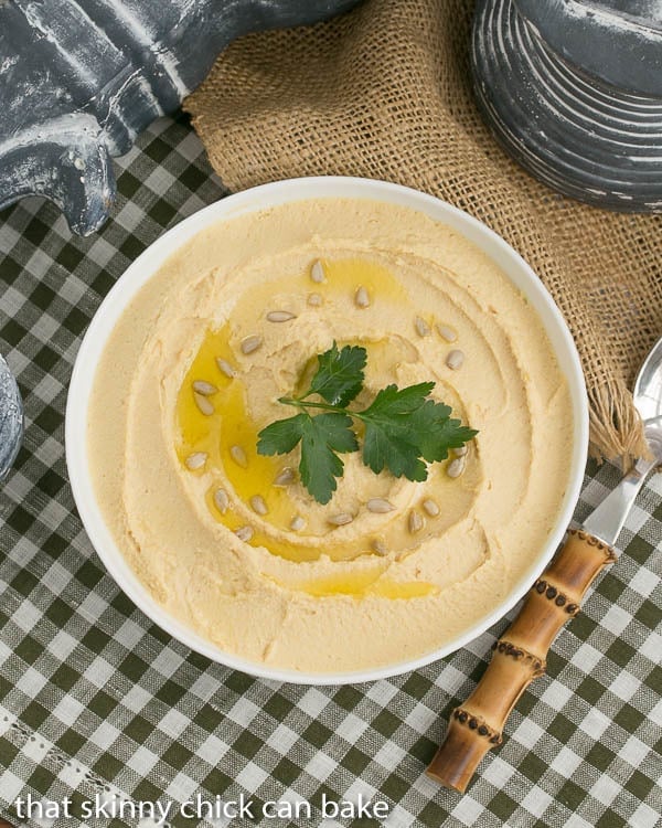 Overhead view of Classic Hummus in a white bowl with a drizzle of olive oil, seeds and parsley to garnish