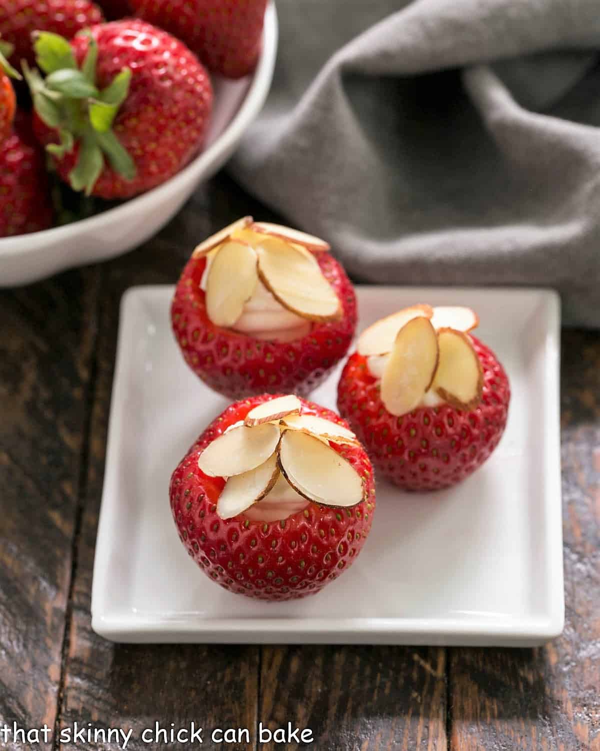 3 stuffed strawberries on a square white plate.