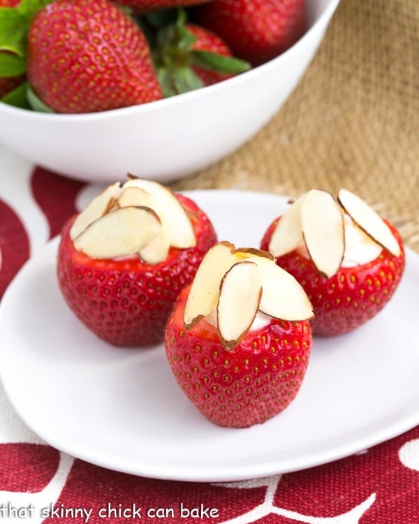 Cheesecake Stuffed Strawberries on a small oval plate topped with sliced almonds.