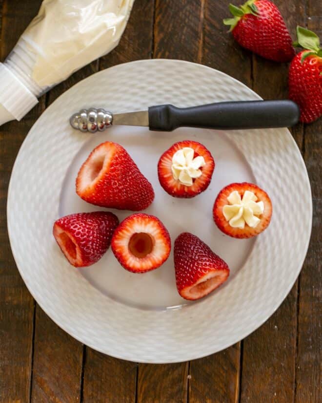 overhead view of coed strawberries and two filled strawberries on a white plate