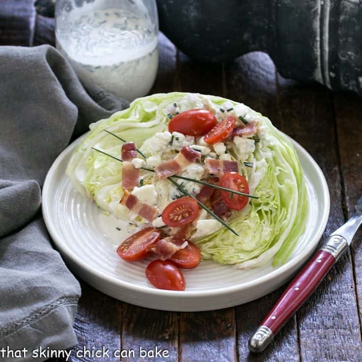 Wedge salad on a round white plate with jar of blue cheese dressing
