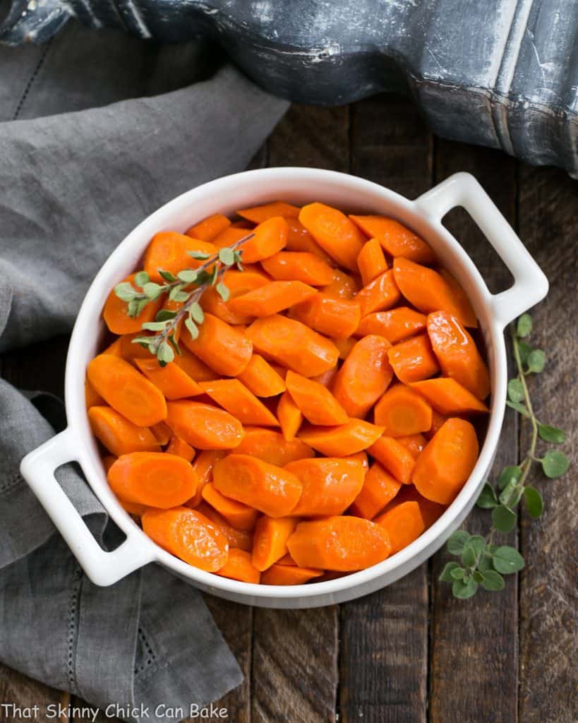 Bourbon Maple Glazed Carrots in a round ceramic dish with herbs