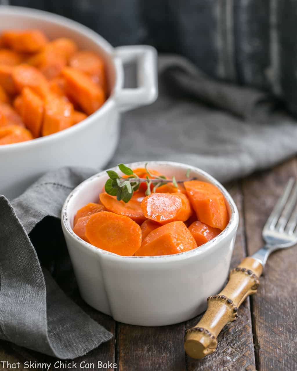 Bourbon Maple Glazed Carrots in a small white bowl with a bamboo fork.