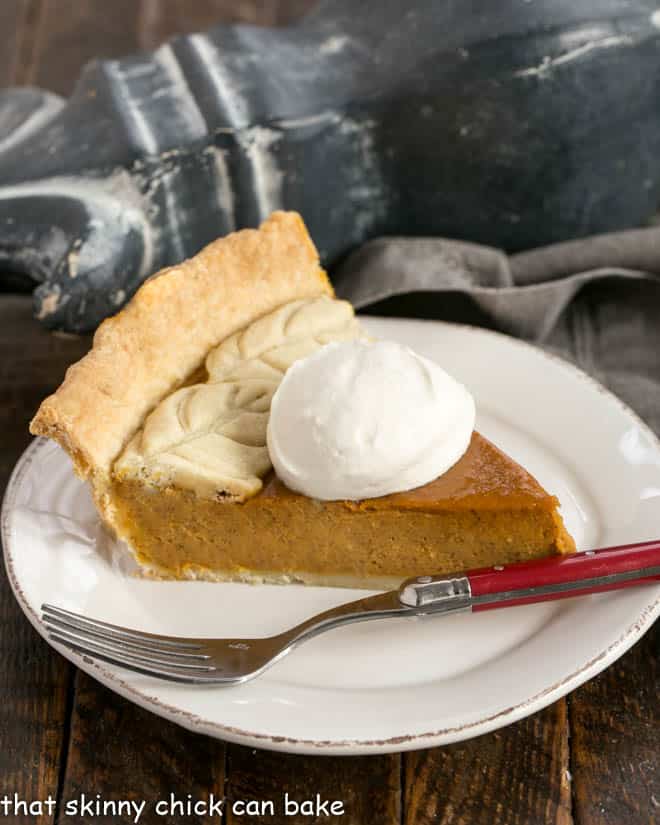 Slice of pumpkin pie on a white dessert plate.