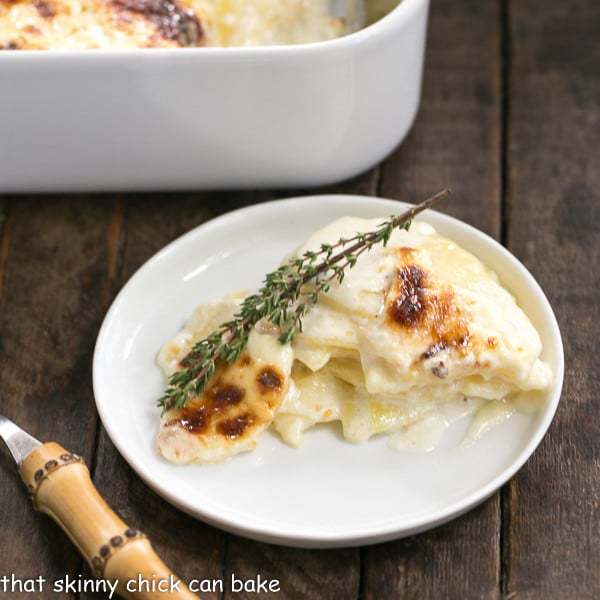 French Potato Gratin on a round white plate with a bamboo handled fork.