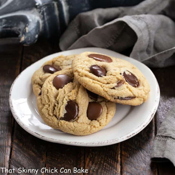 3 chocolate chunk cookies on a round white dessert plate.