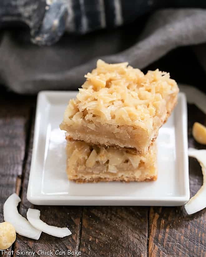 Coconut Macadamia Nut Bars stacked on a square white plate.