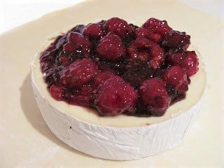 Brie with berry topping on a sheet of parchment