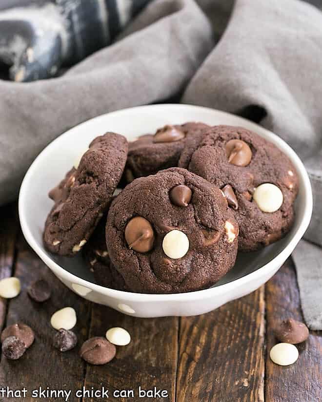 Quadruple Chocolate Cookies in a white bowl surrounded by chocolate chips.