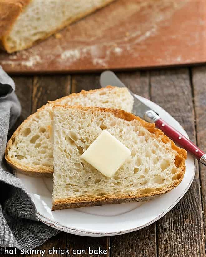 Slices of this Easy Bread Recipe with a pat of butter on a small white plate.