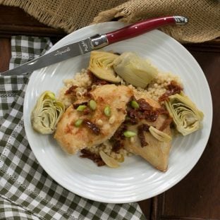 Overhead view of Chicken with artichokes and sundried tomatoes on a white plate