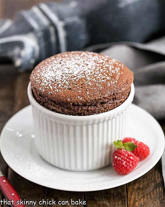 Individual Individual Chocolate Soufflés in white ramekins with a fresh raspberry garnish