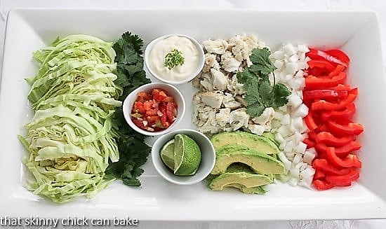 Grilled fish tacos and fixings on a white platter