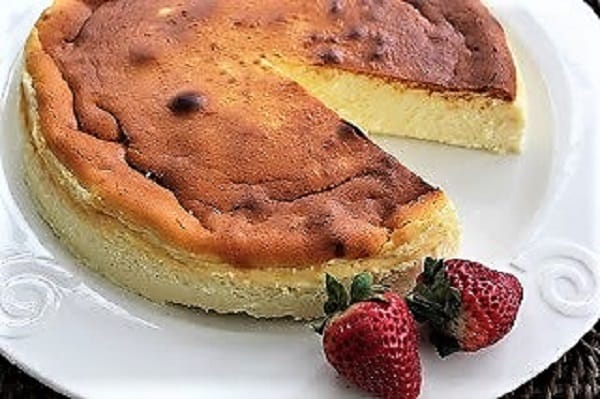 Ricotta Cheesecake with Homemade Ricotta on a white cake plate with a slice removed