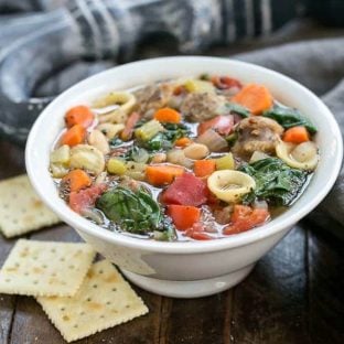 Italian Sausage and Pasta Soup in a white bowl with saltine crackers
