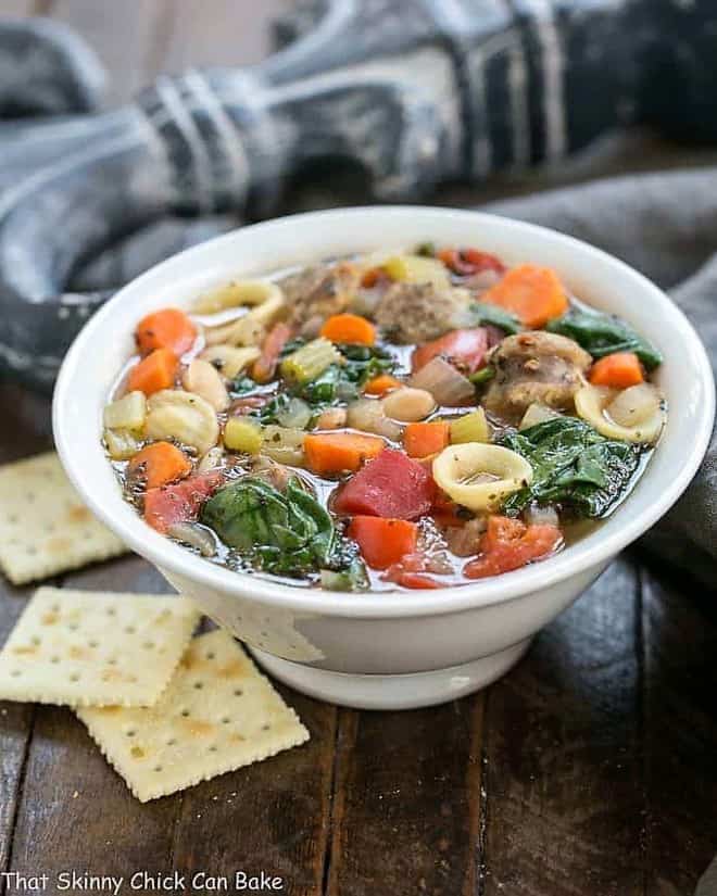 Italian Sausage and Pasta Soup in a white bowl with saltine crackers.