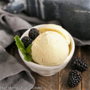 White Chocolate Ice Cream scoops in a white ceramic bowl with berries and mint