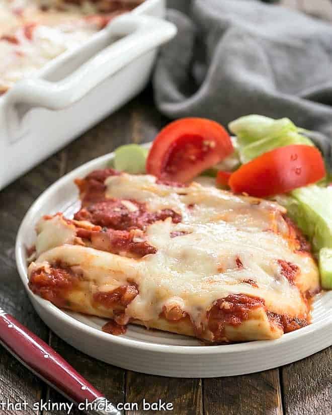 Cheese Manicotti on a white plate with a lettuce salad