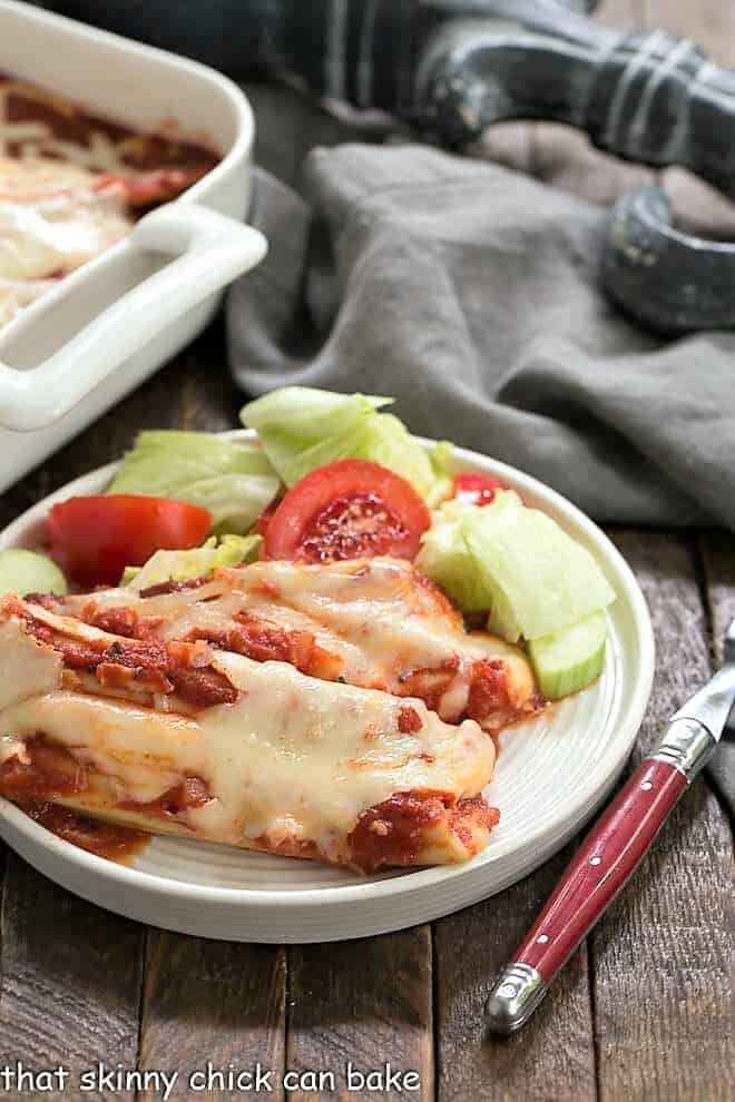 The Best Manicotti on a round white plate with a red handled fork