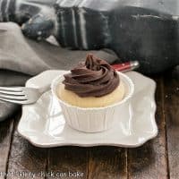A boston Cream Pie Cupcake on white square plate with a red handled fork
