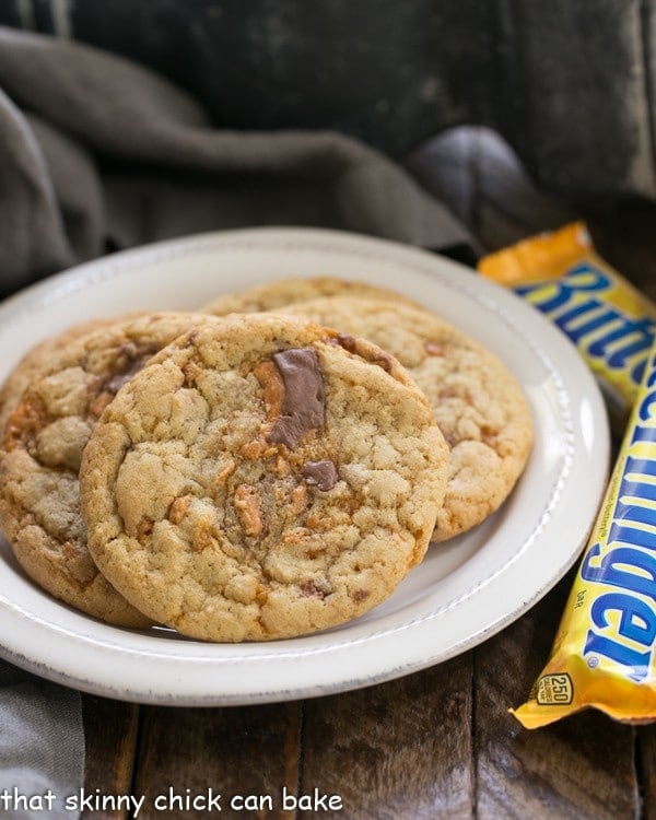 Chewy Butterfinger Cookies on a round white plate with Butterfinger candy bars.