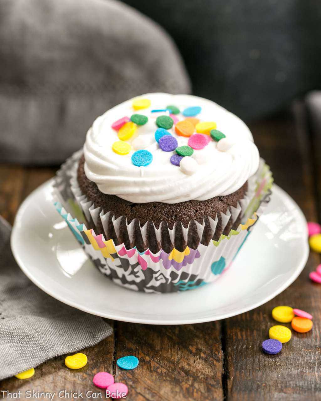 Cocoa Cupcakes with Ganache Filling on a small white plate topped with sprinkles.