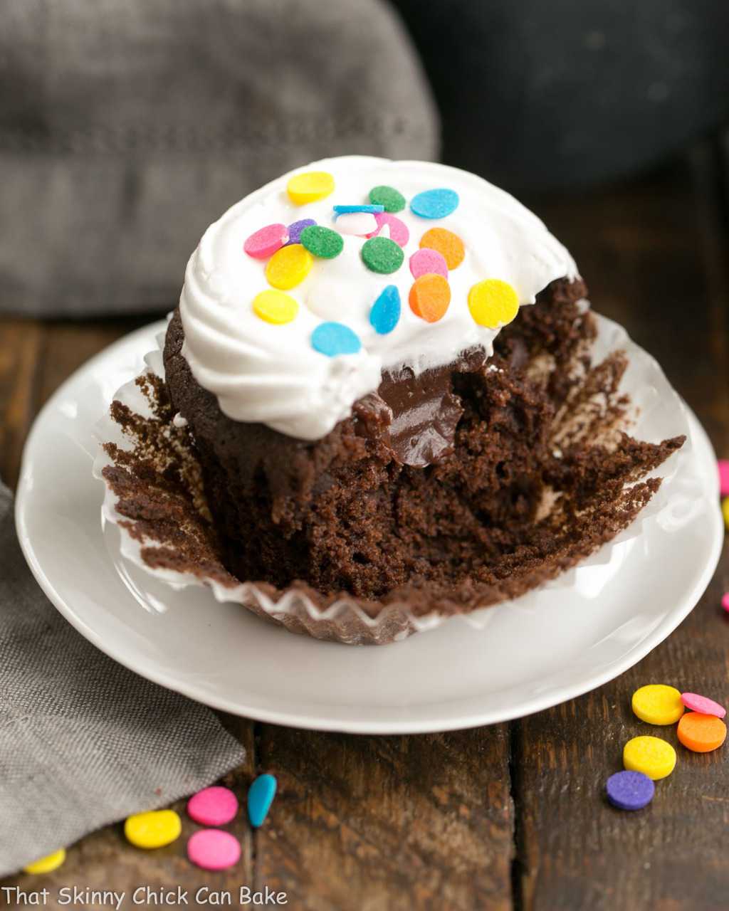 Cocoa Cupcakes with Ganache Filling - a delectable chocolate cupcake with a chocolate surprise in the middle! Inside view of Cocoa Cupcakes with Ganache Filling on a white plate.