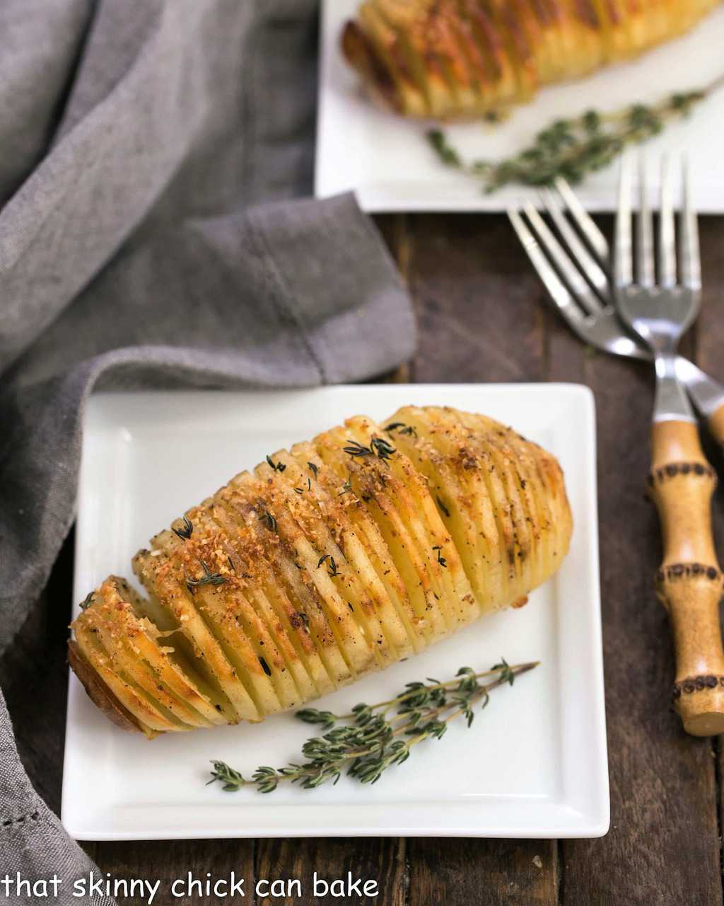 Fanned Potatoes on square white ceramic plates with bamboo forks.