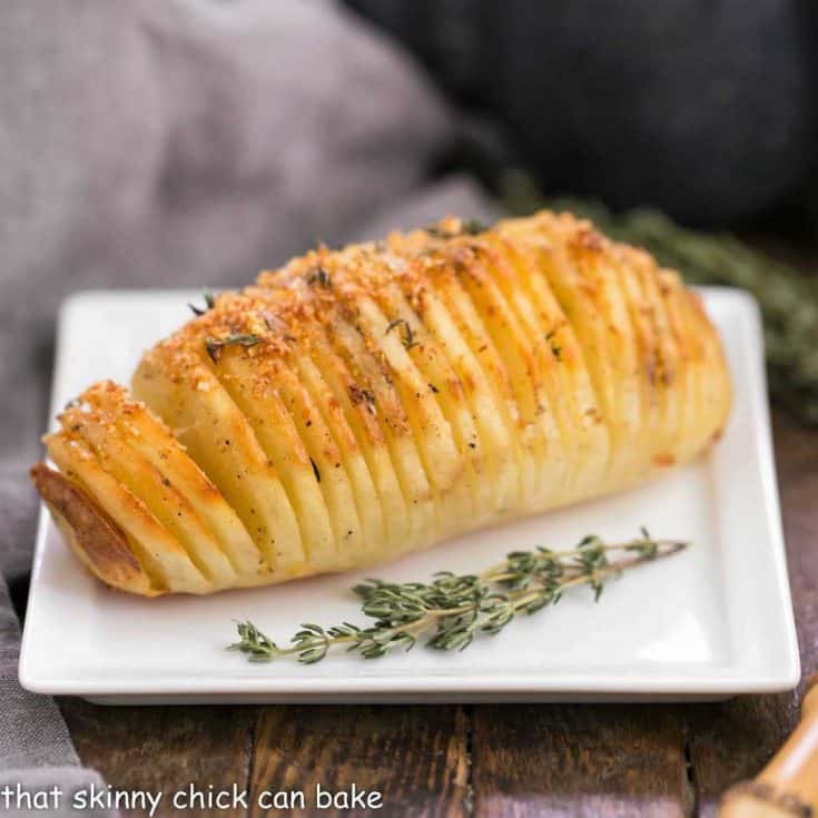 Hasselback Potatoes on a white plate with thyme garnishes
