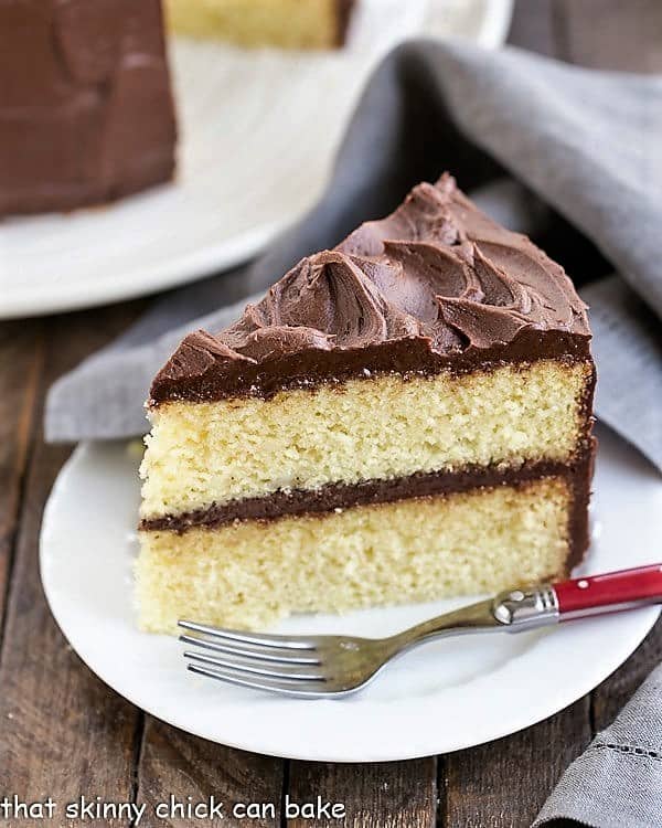 Slice of Perfect Yellow Cake Recipe with Chocolate Buttercream on a white cake with a red handled fork