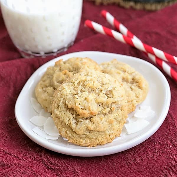 Chewy Coconut Cookies on a white plate with a glass of milk and straws