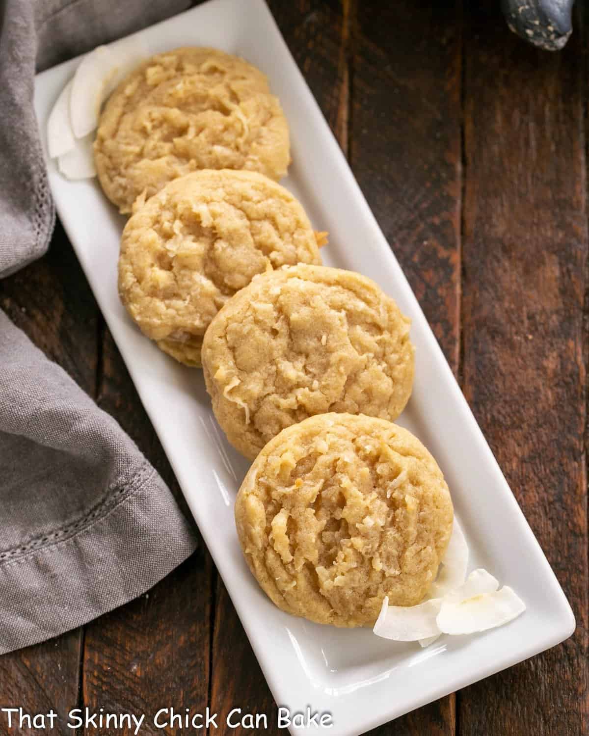 Overhead view of 4 coconut cookies on a white ceramic tray.