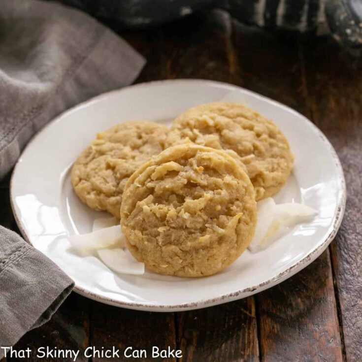 3 coconut cookies on a white ceramic plate.